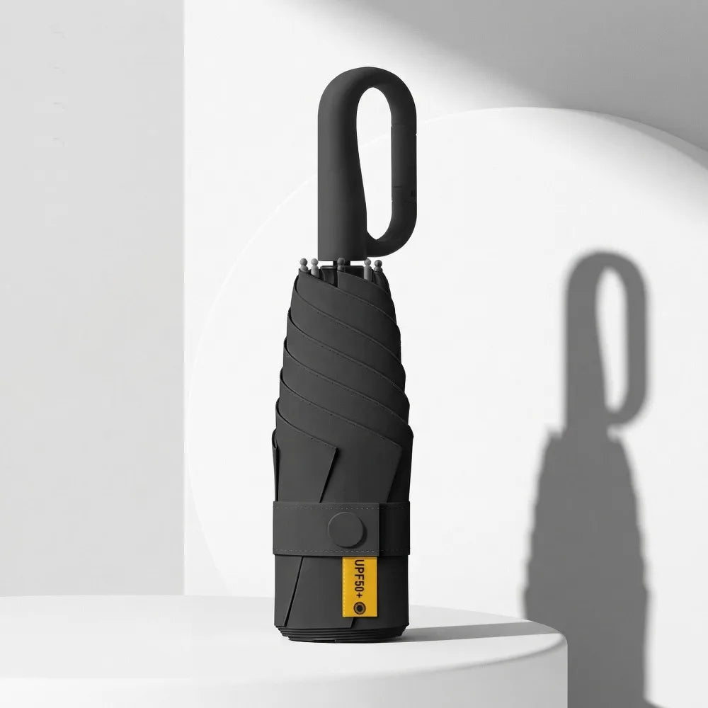A black compact folding umbrella with a handle is shown against a white background.