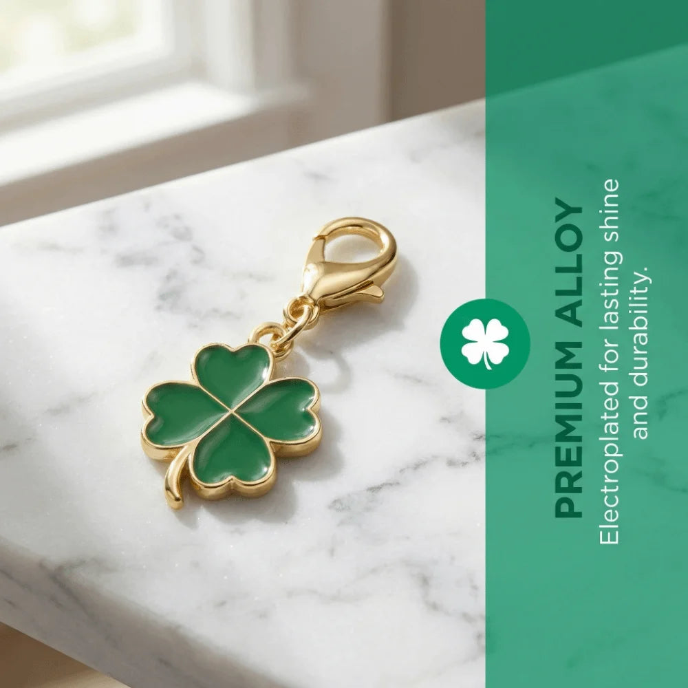 Gold-toned four-leaf clover charm on a white marble surface with green background text.