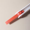 A silicone baby bottle cleaning set with an orange brush and white handle is shown against a light background.