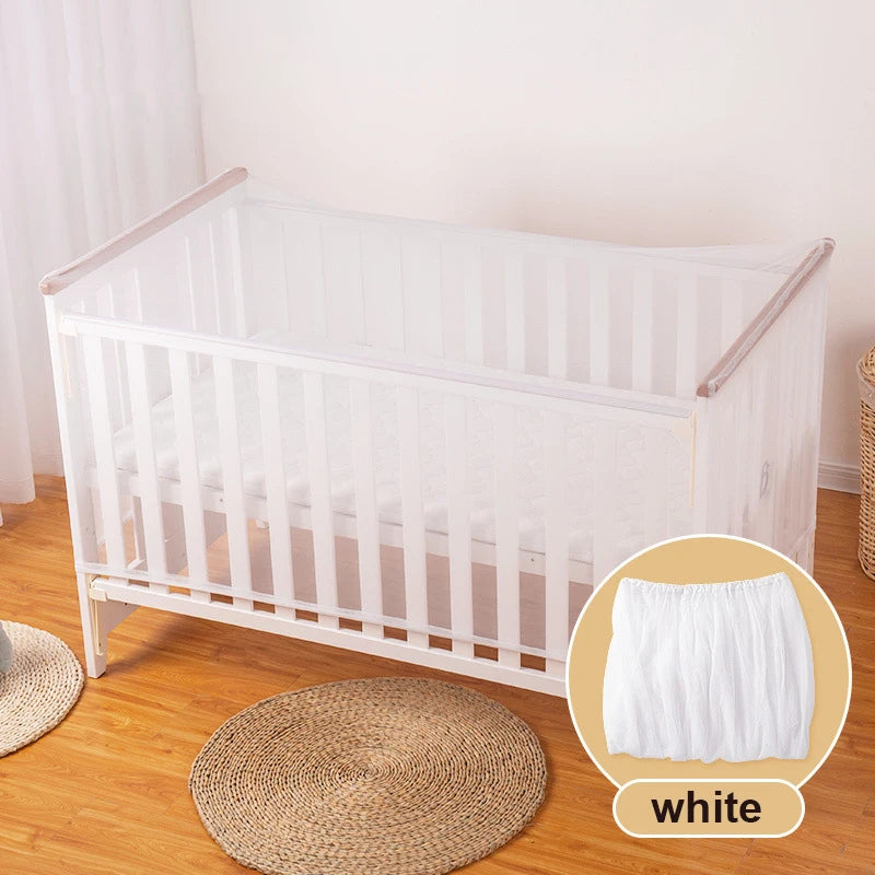 A white breathable mosquito net for baby cribs placed on a wooden floor.