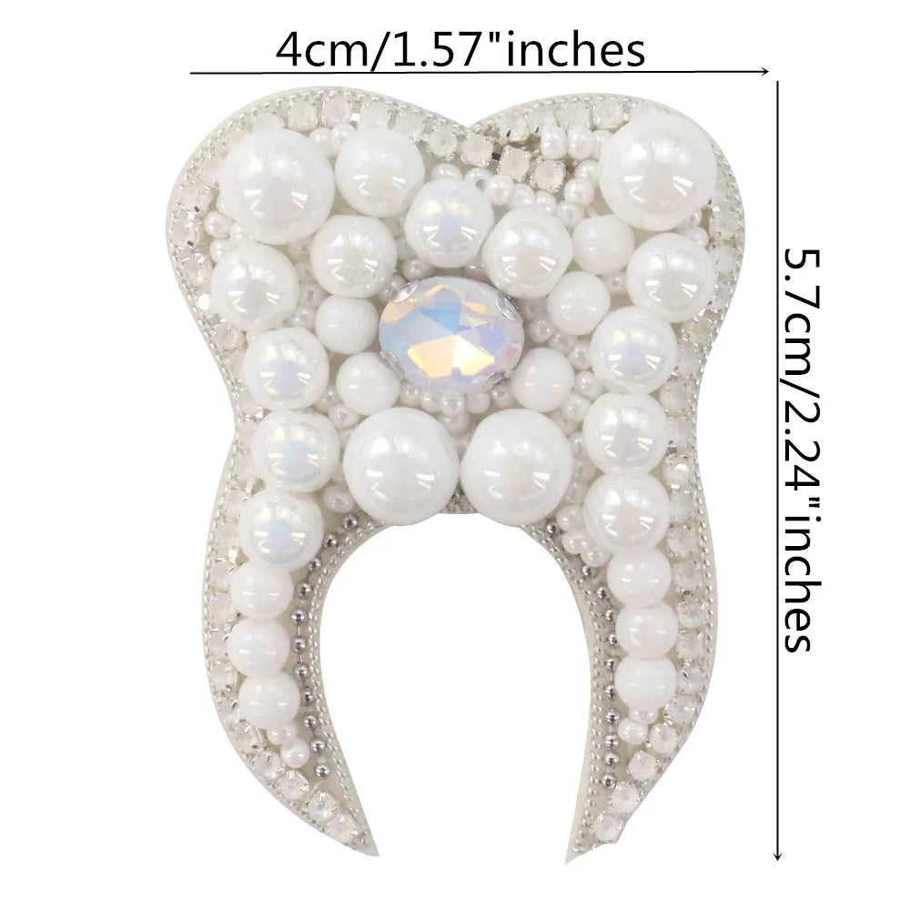 A white pearl and rhinestone flower-shaped brooch or patch with a sparkling center.