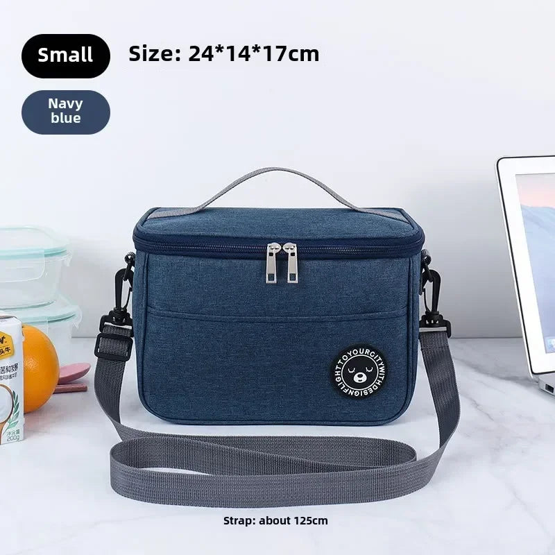 Navy blue insulated lunch bag with a gray shoulder strap shown on a white surface.