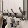 A close-up of a dark gray over-the-door organizer rack with eight hooks mounted on a light wood cabinet door.