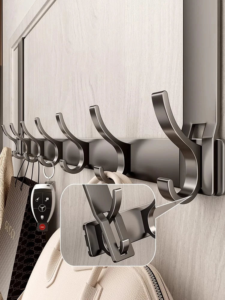 A close-up of a dark gray over-the-door organizer rack with eight hooks mounted on a light wood cabinet door.