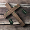 A wooden cross with three green scapular necklaces featuring Saint Jude and Our Lady of Guadalupe.