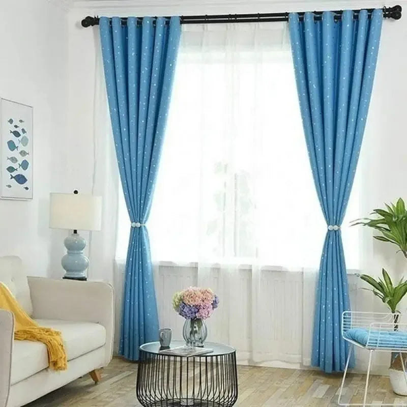 Two blue patterned curtains hanging on a window with white trim and a light-colored wooden floor.