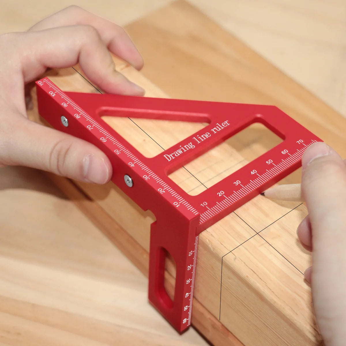 A hand holds a red drawing line ruler with a sliding clamp on a wooden surface for measuring.
