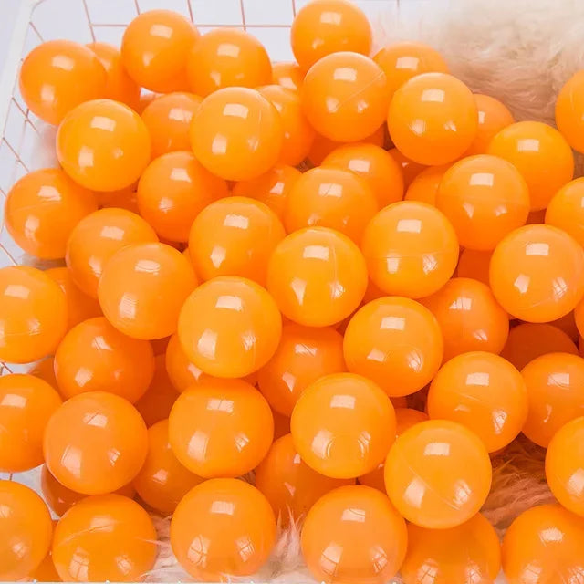 A close-up view of a large pack of bright orange, glossy plastic ball pit balls for toddlers and kids.