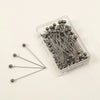 A clear plastic container filled with 100 precision metal quilting pins for sewing and crafting.
