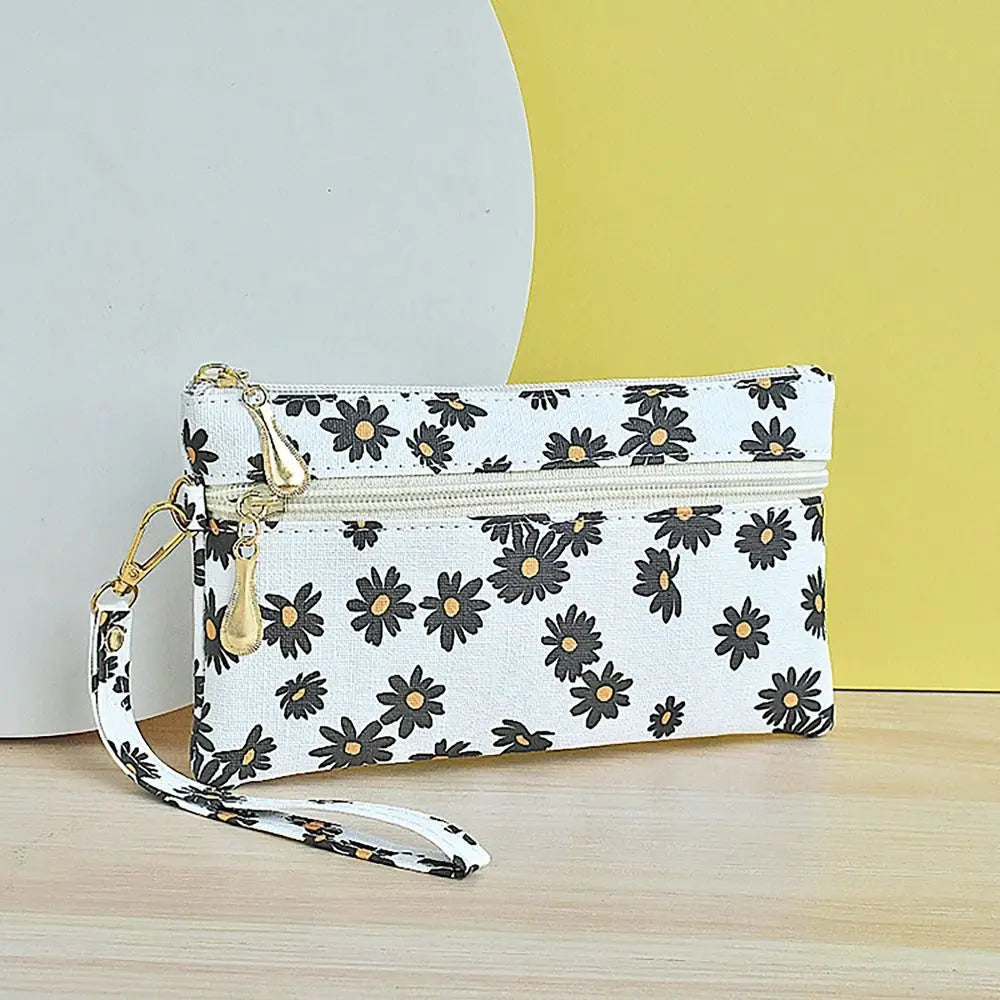 White PU leather wristlet wallet with a black and gray daisy print and gold hardware