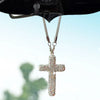A stainless steel rhinestone cross pendant hanging from a rearview mirror.