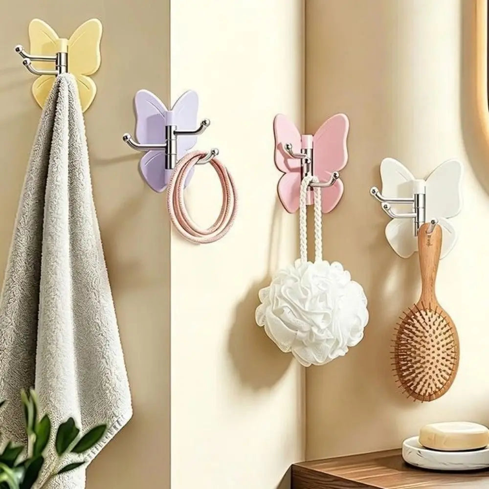 Un juego de ganchos decorativos de mariposa giratoria en rosa y blanco, con un pompon blanco esponjoso y un pincel de madera.