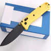 A yellow compact folding knife with a black blade is displayed on a blue and white box.