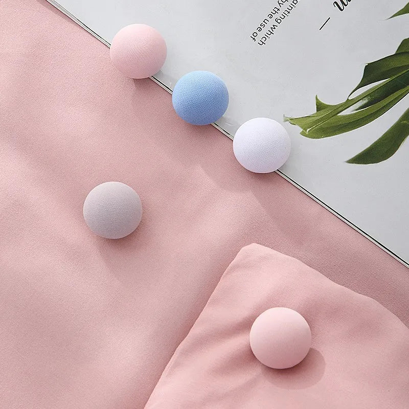 A set of four round, anti-slip quilt clips in various shades of pink and blue are displayed on a light pink fabric.