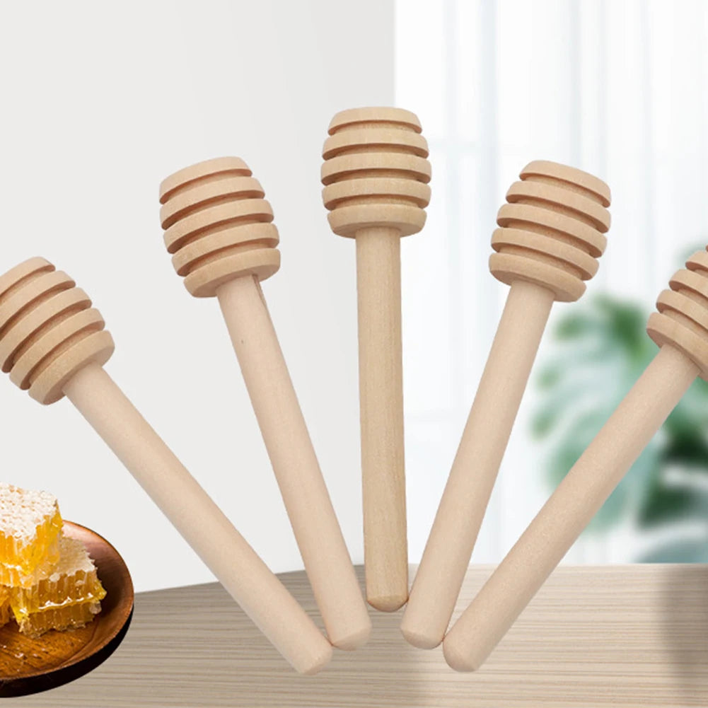A set of natural wood honey dipper sticks with a golden piece of honey on a wooden surface.