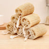 A stack of natural loofah body scrubbers with hanging rope on a wooden surface.