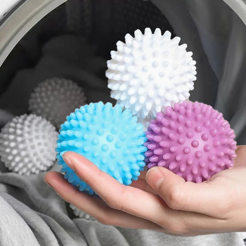 A hand holds a bright blue reusable laundry ball inside a washing machine drum.