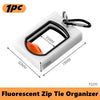 A white fluorescent zip tie organizer with a black clip and measurements shown.