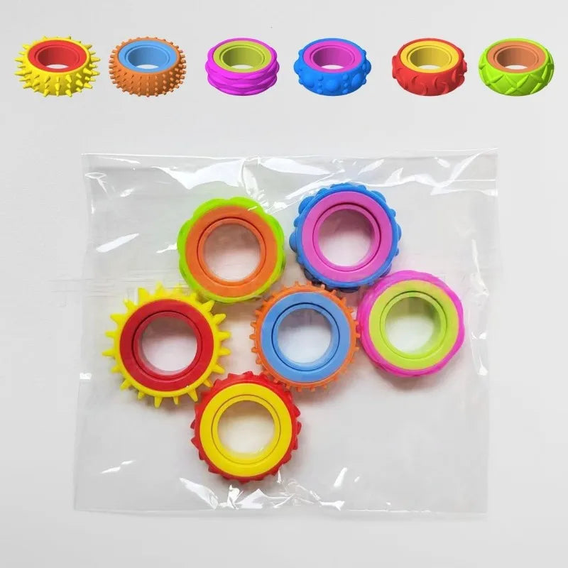 A collection of colorful silicone fidget rings in various colors and textures, packaged in a clear plastic bag.