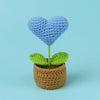Handcrafted crochet heart flower growing in a pot with green leaves