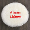 A white, fluffy wool polishing pad disc measuring 6 inches or 150mm resting on a dark wooden surface.