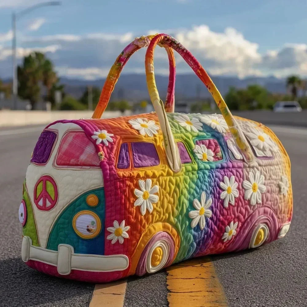 A colorful quilted travel duffle bag shaped like a vintage van with flowers and peace signs resting on asphalt.
