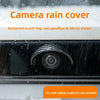 A close-up of a camera rain cover protecting a car's rear camera lens from rain and fog.