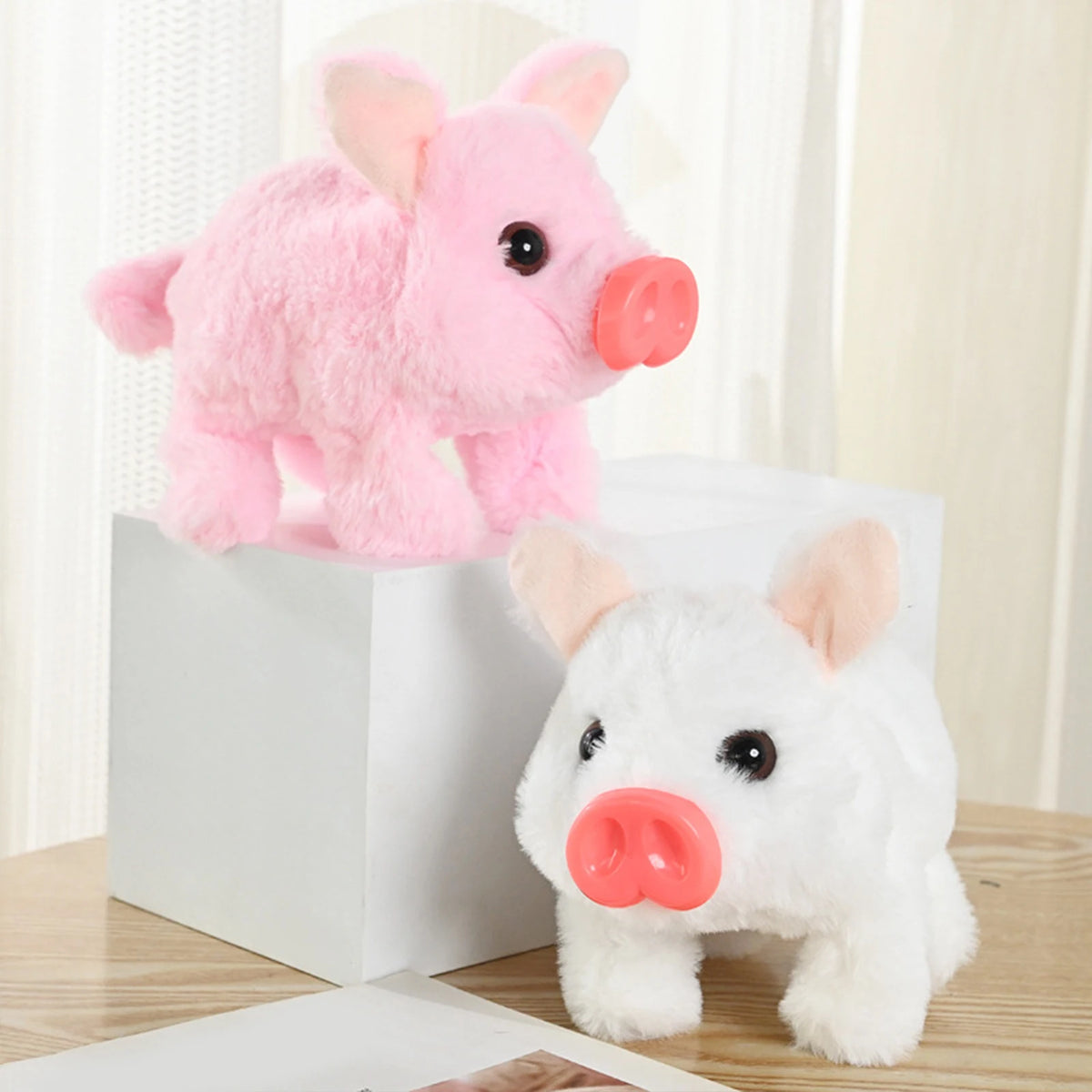 A pink and white plush toy pig, featuring an electronic nose, is displayed in a white box.