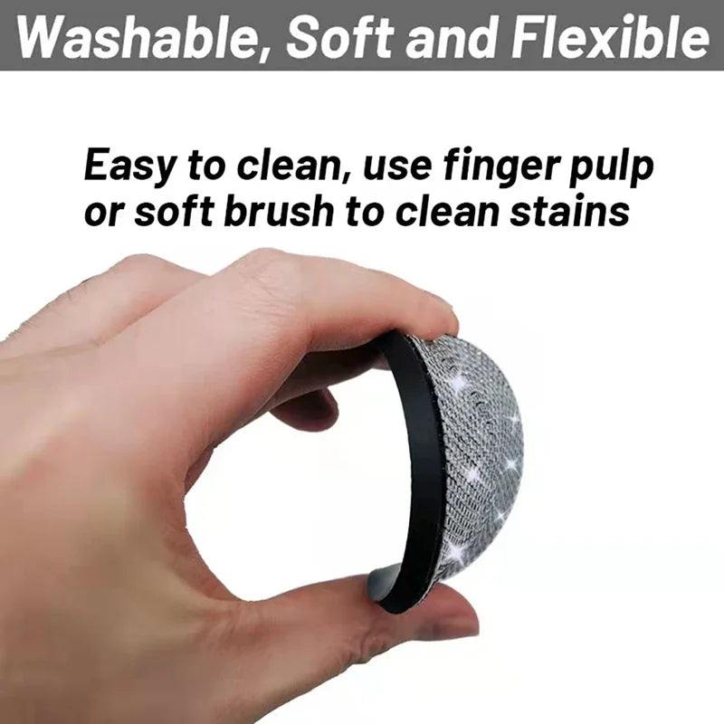 A hand is holding a small, round, silver-colored mesh cleaning tool for stain removal.