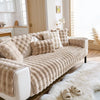 Beige Plüsch-Kaninchenkissen auf weißer Couch, Betonung auf Winterkomfort.