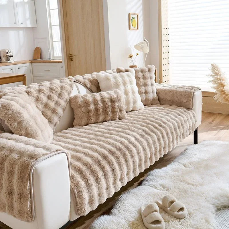Beige Plüsch-Kaninchenkissen auf weißer Couch, Betonung auf Winterkomfort.