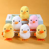 A set of four yellow and pink wind-up walking chicken toys displayed on a light box.