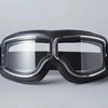 A pair of black retro foldable motorcycle goggles with a clear lens and black strap.