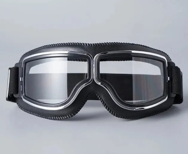 A pair of black retro foldable motorcycle goggles with a clear lens and black strap.