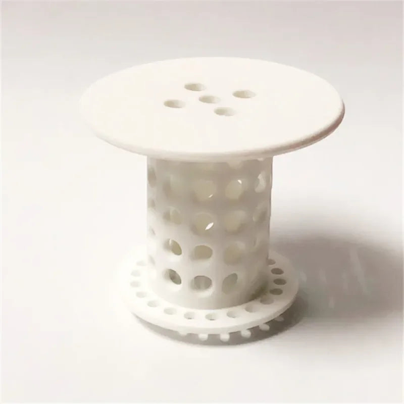 White flexible hair catcher drain cover with multiple holes and a circular base.