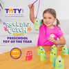 A young girl is playing a green fishing game with a purple fishing rod and various plastic fish toys on a wooden table.