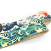 A close-up of a fabric strap featuring a blue and white wave design with an orange sun motif.