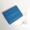 A blue genuine leather slim card holder wallet is shown inside a clear plastic sleeve.