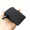 A hand is holding a black patterned utility pouch made of premium materials.