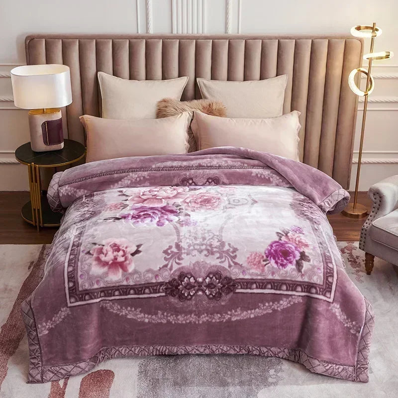 A purple weighted plush blanket with floral embroidery is displayed on a bed and a nearby bedside lamp.
