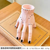 Pink resin Halloween hand planter and pen holder shown on a wooden surface.