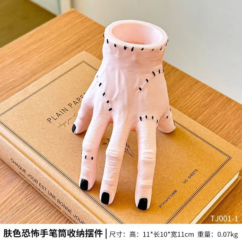 Pink resin Halloween hand planter and pen holder shown on a wooden surface.