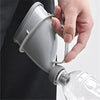 A hand is holding a portable reusable urinal funnel, which is attached to a clear bottle.