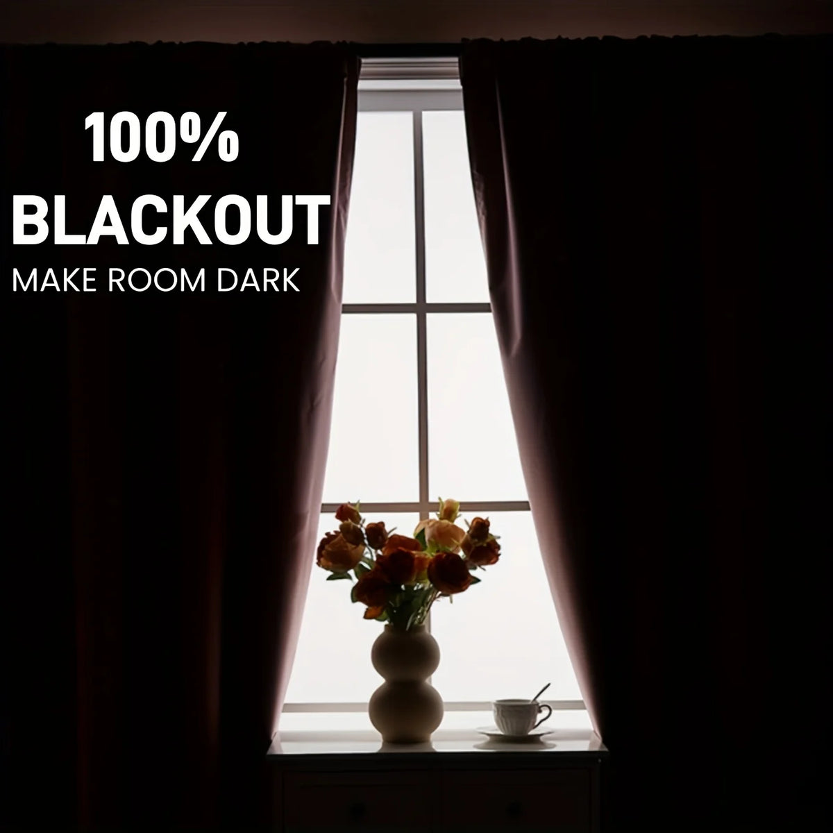 A window with dark blackout curtains framing a vase of orange flowers and a cup on the windowsill.