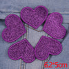 A set of five purple glitter heart iron-on embroidered patches on a denim fabric background.