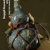 A hand holds a dark blue ceramic gourd wine set secured in a brown net bag.