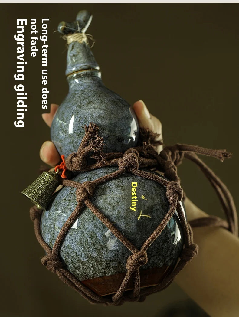 A hand holds a dark blue ceramic gourd wine set secured in a brown net bag.