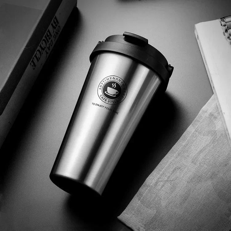 Silberne, isolierte Reise-Kaffeetasse auf dunkler Oberfläche neben einem Tuch.
