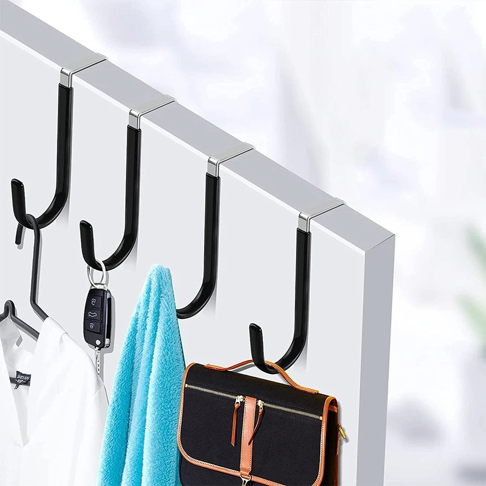 A set of four black over-the-door hooks with soft rubber coating hanging on a white door.