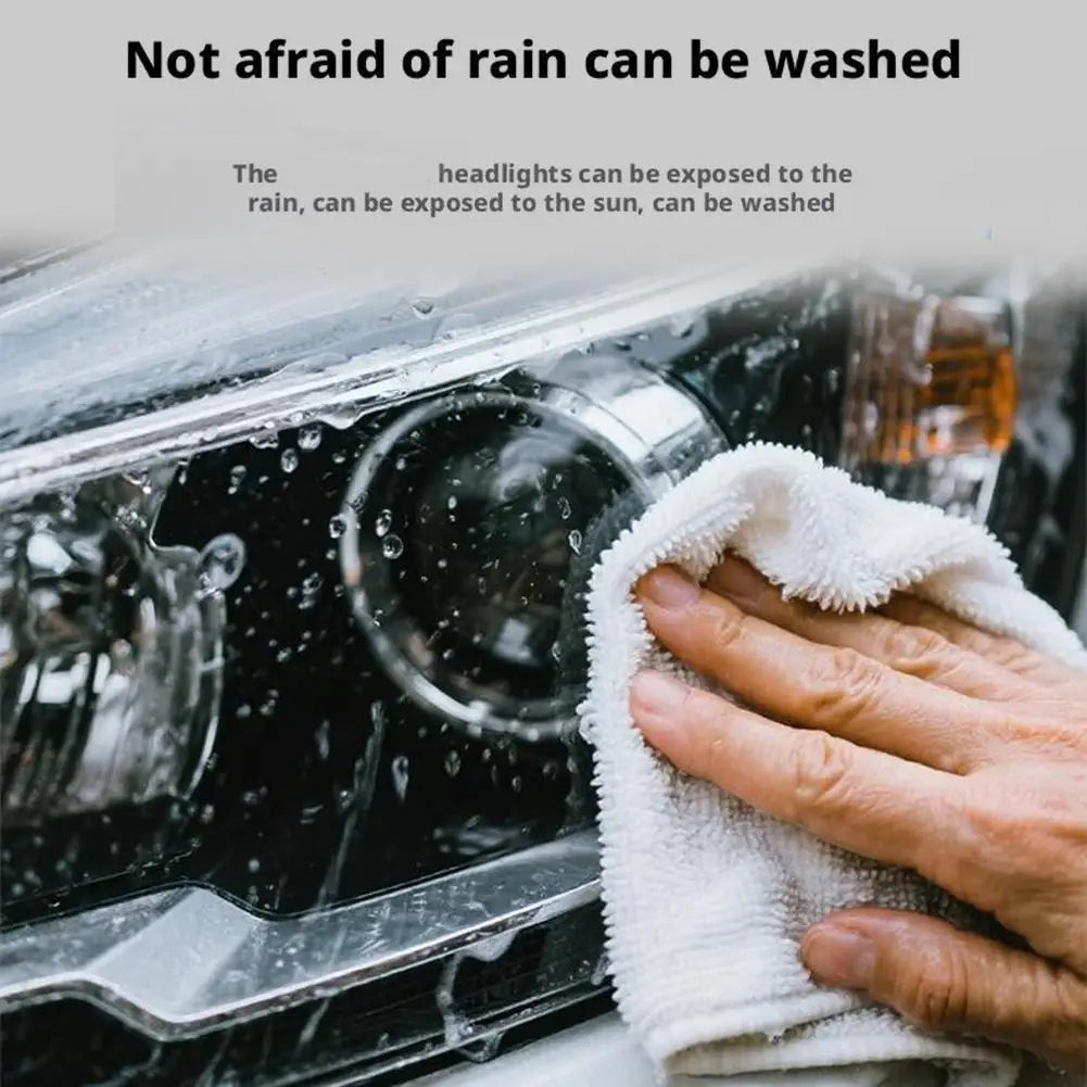 A hand wipes water from a car headlight with a white cloth, demonstrating the ability to wash off rain.